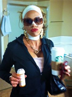 a woman holding two coffee cups in her hands and wearing a bandana around her neck