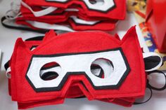 two red and white masks sitting on top of a table next to each other,