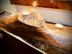 two candles are sitting on a piece of wood