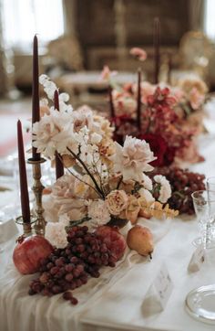 the table is set with flowers, fruit and candles