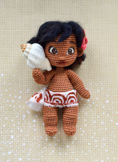 a crocheted doll with a shell in her hand