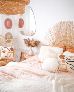 a bed with pink sheets and pillows in a room that is decorated with wicker decorations