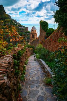 a stone path leading up to a building on the side of a hill next to water