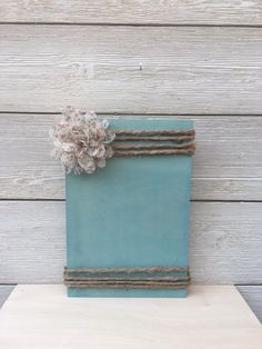 a small blue box with a flower on the top is sitting on a table next to a wooden wall