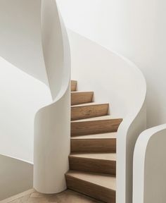 there is a spiral staircase in the room with white walls and wood flooring on the side