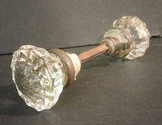 an old glass door knob with a wooden handle on a black counter top in front of a gray wall