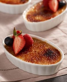 three small white dishes filled with fruit on top of a table