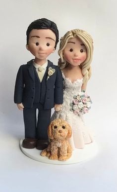 a wedding cake topper with a bride and groom standing next to a brown dog