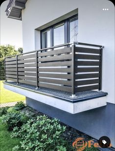 a balcony with metal railings on the side of a house in front of grass and bushes