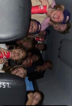 a group of people are sitting in the back of an airplane and one person is holding a cell phone up to their ear