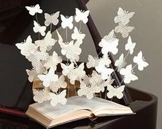 an open book sitting on top of a piano with paper butterflies flying out of it