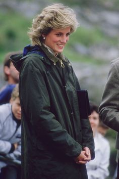 the woman is wearing a green coat and smiling