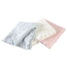 three different colored knitted blankets sitting on top of each other