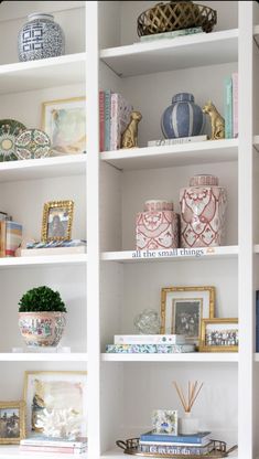 a white book shelf filled with lots of books and vases on top of it