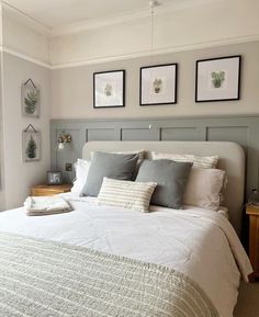 a white bed sitting in a bedroom next to two framed pictures