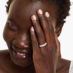 a woman smiles as she holds her hand up to her face and wears a diamond ring