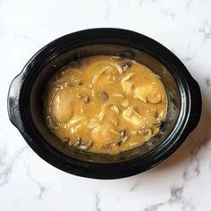 a black crock pot filled with food sitting on top of a white marble counter