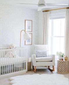 a baby's room with a white crib, rocking chair and large window