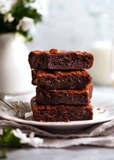 chocolate brownies stacked on top of each other on a plate next to a glass of milk