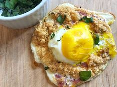 an egg on top of bread next to a bowl of greens