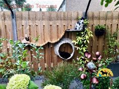 a cat house in the middle of a garden with flowers and plants growing around it