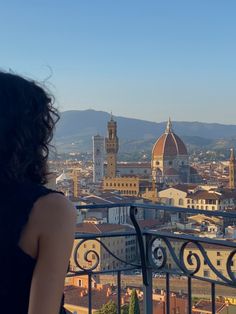 a woman standing on top of a balcony looking at the city