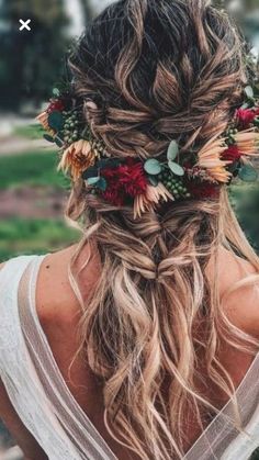 a woman with long hair and flowers in her hair is looking down at the ground