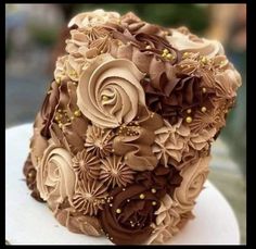 a bridal bouquet made out of chocolate and gold flowers on a white cake plate