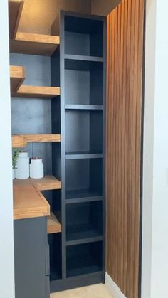 an empty pantry with wooden shelves and white walls