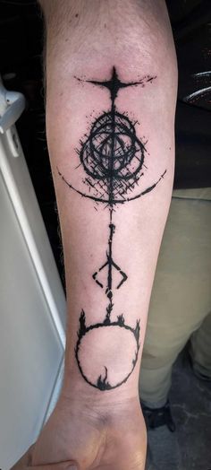 a person with a tattoo on their arm holding up a clock and compass in front of them