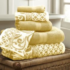 yellow towels stacked on top of each other in a basket next to a toilet and sink