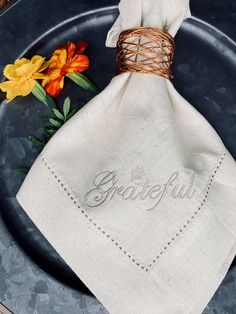 a napkin with the word grateful written on it sits on a plate next to flowers