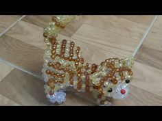 a glass beaded cat sitting on top of a wooden floor next to a tile floor