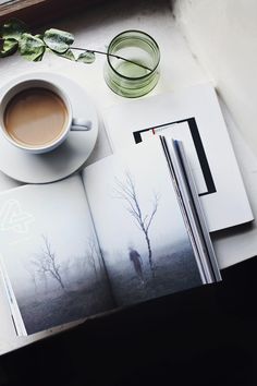 an open book on a table with a cup of coffee