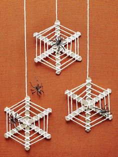 three spider ornaments hanging from strings on an orange wall next to a black and white spider