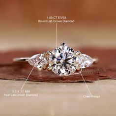 an engagement ring with three pear shaped diamonds on the side, and four claw prongs