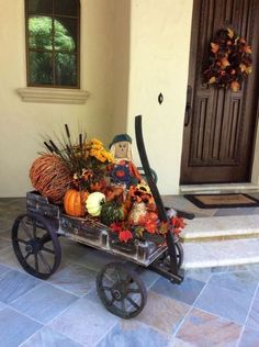 a wagon filled with pumpkins and gourds sitting in front of a house