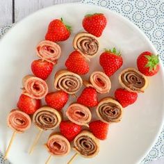 strawberries are arranged in spirals on a plate with toothpicks and strawberries