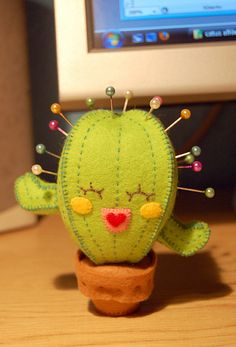 a green stuffed cactus sitting on top of a wooden table