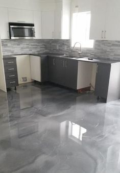 an empty kitchen with white cabinets and grey marble flooring, as well as stainless steel appliances