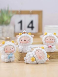 three little sheep figurines sitting on top of a wooden block in front of a clock