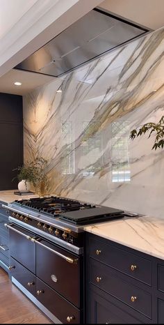 a kitchen with marble counter tops and black cabinets, along with a stove top oven