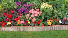 a wooden planter filled with lots of colorful flowers next to a lush green field