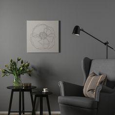 a living room with two chairs and a table in front of the chair is a drawing on the wall