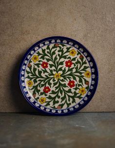 a blue and white plate sitting on top of a counter next to a tile wall