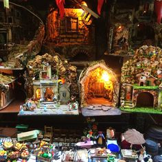 an assortment of miniature houses and figurines on display in a room with lights