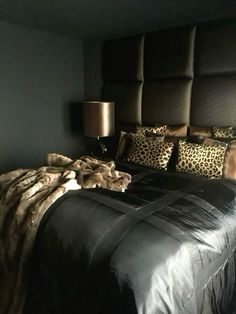 a large bed with leopard print pillows and blankets on it's headboard in a bedroom