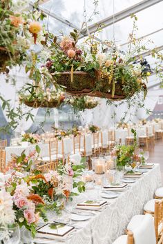 a table set up with flowers and greenery for a wedding reception in a greenhouse