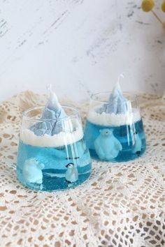 two glasses filled with blue liquid sitting on top of a doily