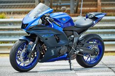 a blue and black motorcycle parked on the side of a road next to some steps